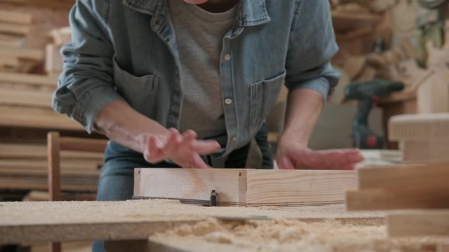 Female carpenter processes parts and assembles a wooden product.