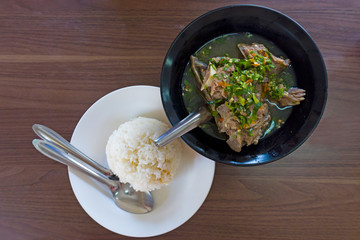 Top view composition of various Asian food on wooden table, Hot and Spicy Soup with Pork Ribs and Streamed rice.