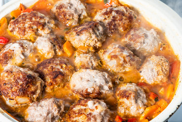 Delicious meatballs in homemade tomato sauce sprinkled with grated cheese in a large enameled pan