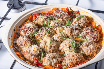 Delicious meatballs in homemade tomato sauce sprinkled with grated cheese in a large enameled pan