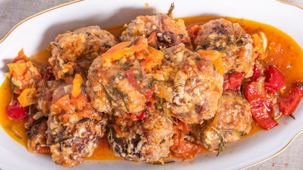 Delicious meatballs in homemade tomato sauce baked with grated cheese and rosemary leaves on a dish close-up - american cuisine
