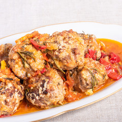 Delicious meatballs in homemade tomato sauce baked with grated cheese and rosemary leaves on a dish close-up - american cuisine