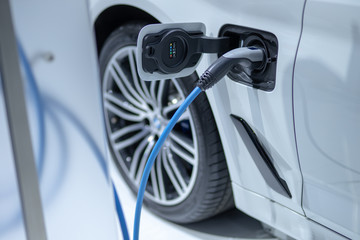 EV Car or Electric car at charging electric car battery station with power cable supply plugged in white modern car. Eco-friendly alternative energy Innovation future concept.