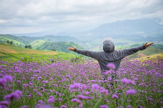 Happy of man standing alone on mountain with open arms raised up in verbena purple flower field in the morning. Enjoying  nature