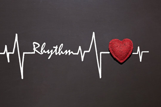 red texture heart on a black chalk board, a chart of a cardiogram is drawn with chalk and the word RHYTHM is written. Heart healthy concept
