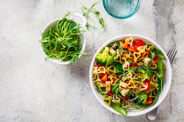Valentine's Day concept. Salad with pasta hearts, olives, tomatoes, spinach and broccoli in a white bowl.