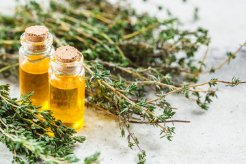 Thyme essential oil in glass bottles, gray background, copy space.