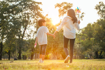 Family and Vacation Time concept.Happy Young Family Mother and son walked to hold hands looks happy in the park in the afternoon autumn sunlight,bokeh,Sunny Day Sunset,happily holiday with copy space.