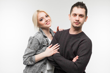 portrait of a young family of man and woman seated in an embrace on a light gray background
