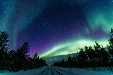 Northern lights Aurora Borealis activity over the road in Finland, Lapland