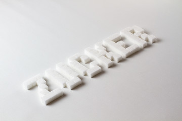 "Sugar" (Zucker in German) spelled with pixel art letters made out of sugar cubes on a white background