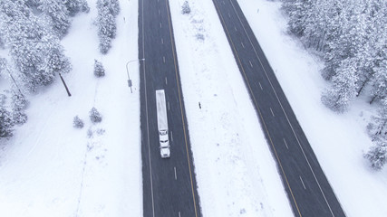 AERIAL: Flying above a truck speeding along slippery highway during a blizzard.