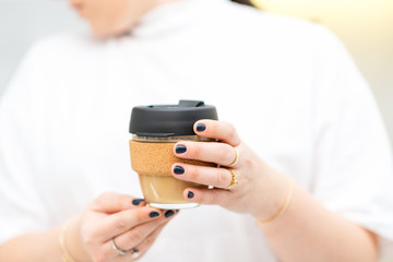 Woman hands hold reusable glass coffee cup. Sustainable living. Eco friendly, zero waste concept.
