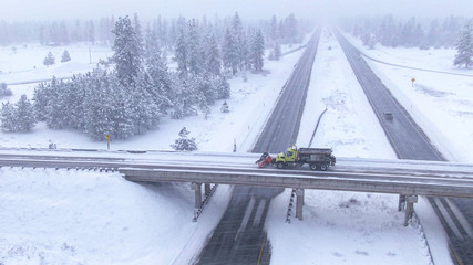DRONE Truck plows a road crossing the interstate highway in wintry United States