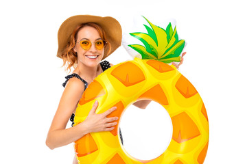 lovely girl in a straw hat with a pineapple shaped swimming circle on a white background