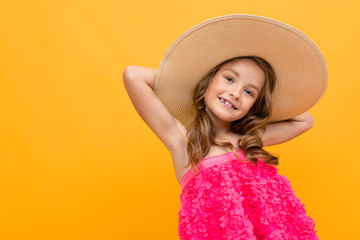 portrait of a charming cute young child with a straw haton a yellow background with copy space