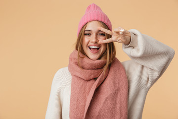 Image of young girl in winter hat smiling and showing peace fingers