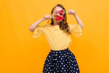 attractive caucasian young girl in a skirt and a t-shirt with two watermelon lollipops posing on a yellow background