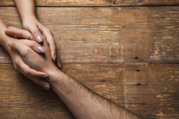 woman and man hand in hand on the wooden desk