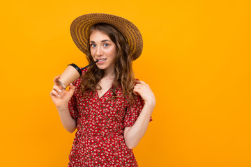 portrait of charming stylish smiling girl in a hat with a paper cup on a yellow background