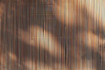 light and shadows on outdoor wooden battens background and texture. timber slat partition for home...