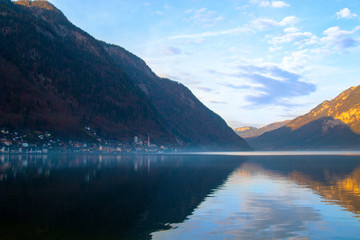 Panoramic view of old historic town Hallstatt surrounded by mountains on the tranquil lake with reflection of sky and hills