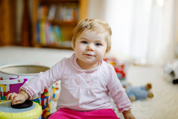 Lovely beautiful cute beautiful little baby girl playing with educational toys at home or nursery. Happy healthy child having fun with colorful different toys. Kid learning different skills.