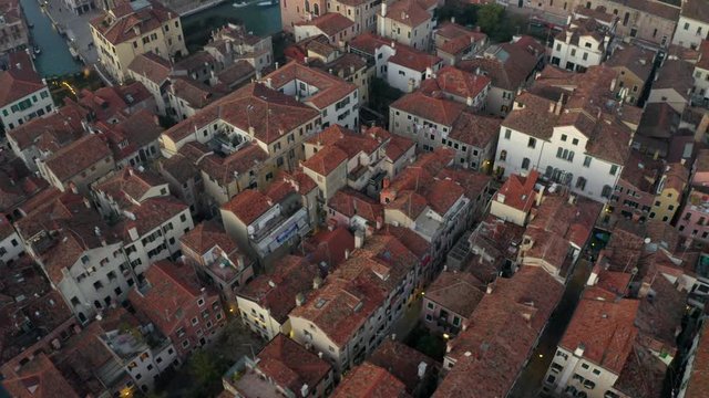 Aerial, tracking, drone shot over buildings and Venetian architecture, at a evening, in Venezia, Italy
