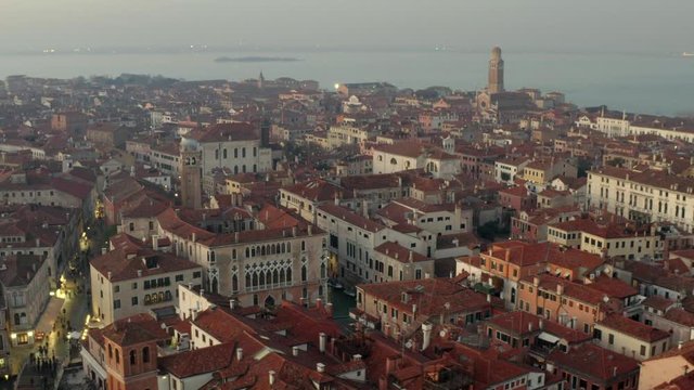Aerial, tracking, drone shot overlooking buildings and Venetian architecture, at a evening, in Venice, Italy