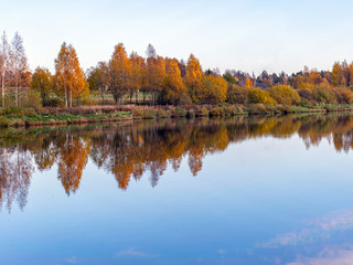 landscape with trees and clouds reflecting in calm water