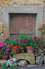 An old wooden door with surrounding stonework and planted geraniums  in Provence South of France