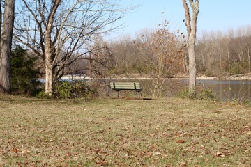 The empty park bench on the riverbank by the river.