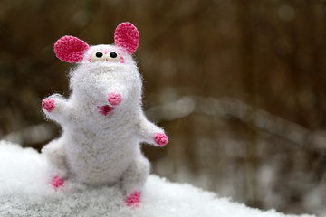 White knitted toy rat on the snow in winter forest, New Year card. Chinese Year of Rat, Zodiac symbol 2020