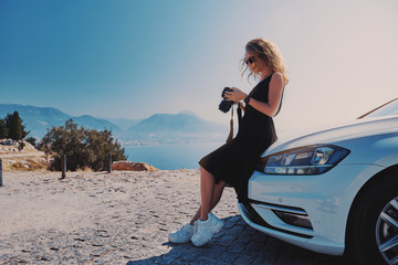 Beautiful woman professional photographer standing with dslr camera near her car while travel in Turkey
