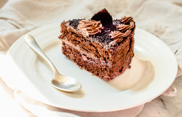 Piece of chocolate cake in a white plate and gold cup of coffee, closeup. Selective focus.