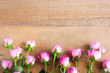 Small pink roses on a background of unpainted and untreated boards. Valentine's day composition, selective focus.