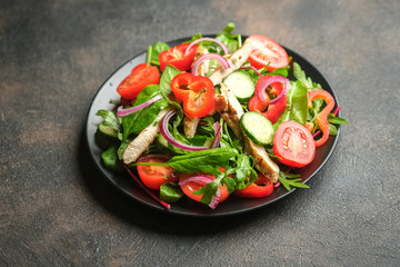 Fresh vegetable salad with chicken meat, herbs and olive oil in a dark plate on a dark background. Healthy food. Top view copy space.