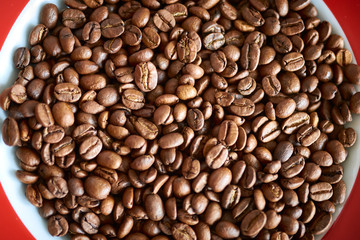 Nahaufnahmen von braunen Kaffeebohnen auf einem Teller mit roten Ecken
