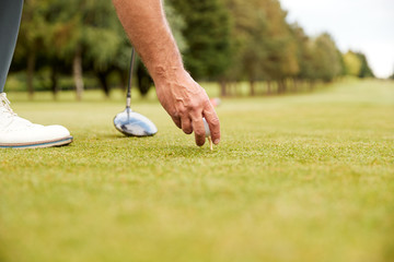 Close Up Of Mature Male Golfer Preparing To Hit Tee Shot Along Fairway With Driver