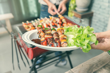 A man with a barbecue plate at a party between friends. Food, people and family time concept.