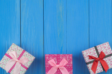Three gift boxes on bule wooden background. Place the gift box below so that there is a message box on top.