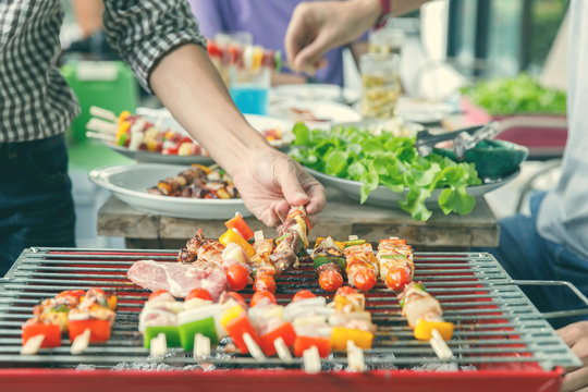 A man grilling pork and barbecue in dinner party. Food, people and family time concept.