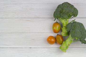 Fresh tomatoes  and broccoli on the white wooden table.