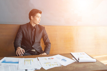 The young business man sat with a relaxed expression, looking out the window and working on the papers.