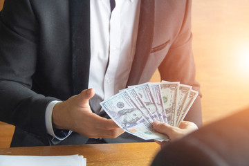 Close-up of businessman hand giving money to other hand - United States Dollars (or USD) and receiving money, corruption concept