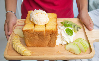 Hand holding Honey Santos with vanilla ice-cream and whipped cream, In the cafe popular among students. Honey Toast is a dessert made from the pound bread.
