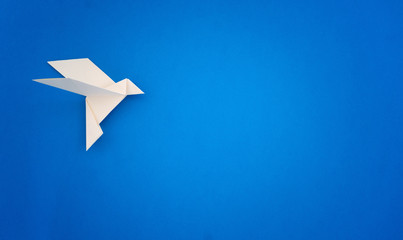 Fototapeta na wymiar White origami bird on blue background minimalist