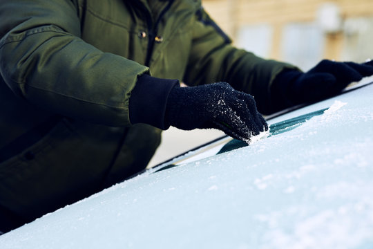 Close Up Of Man Scraping Ice From The Windshield Of A Car