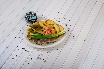 Delicious appetizer of pickles, potatoes, onions and salted fish all shot on a white background