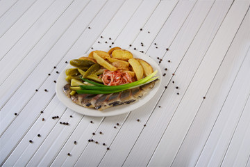 Delicious appetizer of pickles, potatoes, onions and salted fish all shot on a white background